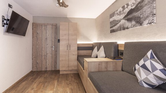 A modern room with wooden decor and cozy seating areas. A television and a picture of a landscape hang on the wall. - Haus Manfred - Sölden