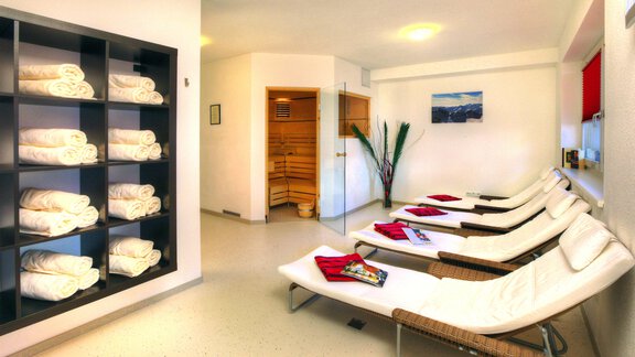 A relaxing wellness area with loungers and a towel. In the background, a sauna and a plant are visible. - Haus PIA by A CASA - Sölden