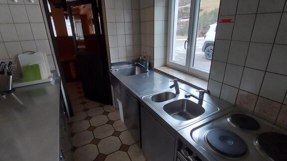 A modern kitchen with stainless steel countertops and multiple sinks. The window offers a view outside. - Haus Pitzwald - Sölden