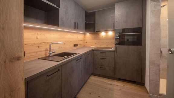 A modern kitchen with wood and dark elements. It is brightly lit and offers plenty of storage space. - Haus Sonnwend - Sölden