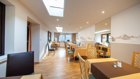 A modern restaurant with light wooden flooring and large windows. The tables are neatly set and create an inviting atmosphere. - Haus Stefanie - Sölden