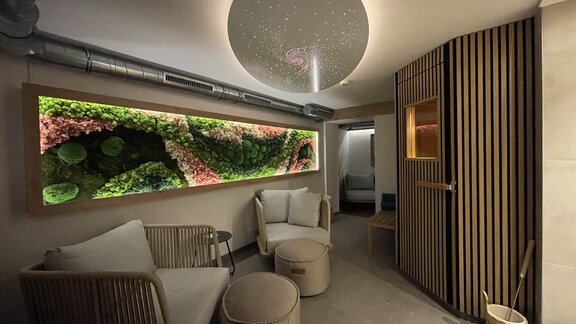 A modern wellness room with a vibrant moss wall and comfortable seating. Soft lighting creates a relaxing atmosphere. - Haus Tanja - Sölden
