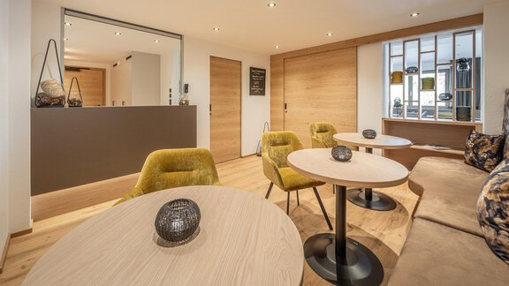 A modern interior design with bright wooden elements and cozy seating areas. The tables are round, and the overall atmosphere is friendly and inviting. - Haus Ulrich - Sölden