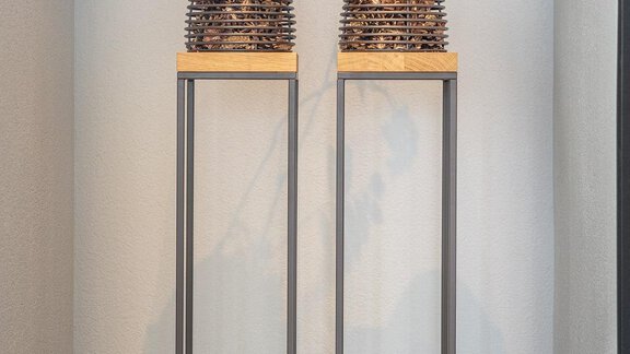 A modern decoration arrangement with two woven baskets on tall stands and a third basket on the floor. The baskets are decorated with artificial flowers, adding an inviting atmosphere to the room. - Haus Ulrich - Sölden