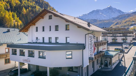 A modern building with the sign "RESTAURANT" on the facade. In the background, majestic mountains and a picturesque landscape can be seen. - Haus Ulrich - Sölden
