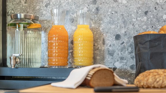 A stylish kitchen with fresh juices in elegant glass carafes. On the table are bread and a cloth napkin. - Haus Ulrich - Sölden