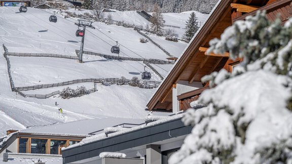 A wintry mountain landscape with snow-covered slopes and ski lifts. In the foreground, modern chalets can be seen. - Haus Ulrich - Sölden