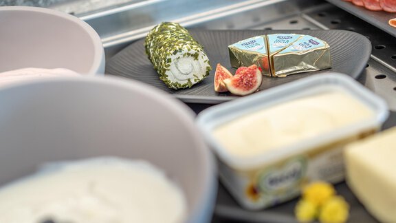 A stylish arrangement of cheese varieties and cold cuts on a plate. Fresh figs and various creams are visible. - Haus Ulrich - Sölden