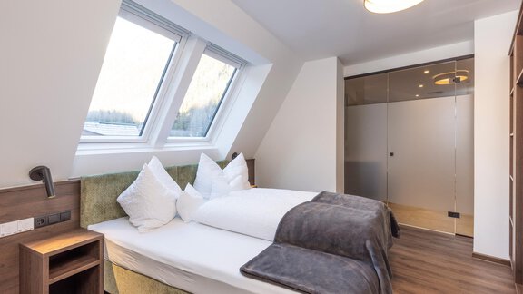 A modern bedroom with two beds, stylish pillows, and a cozy throw. Large windows provide plenty of daylight and a welcoming atmosphere. - Home4You - Sölden