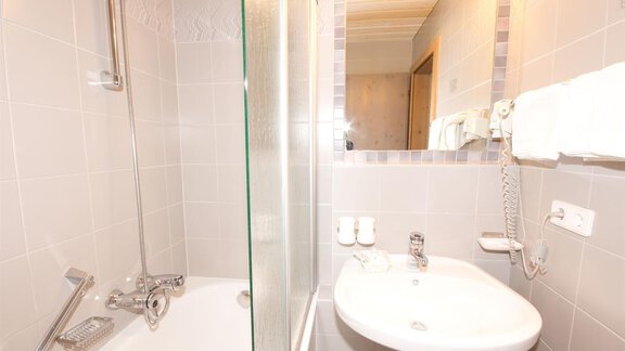 A modern bathroom with a shower and bathtub. Towels and basic sanitary facilities are available. - Hotel Garni Hainbacherhof - Sölden