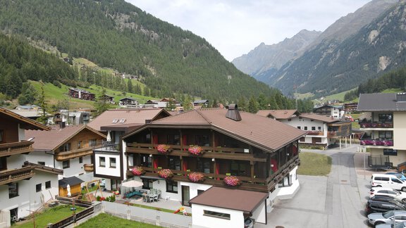 A picturesque alpine landscape with a charming hotel and green meadows. In the background, majestic mountains can be seen. - Hotel Garni Maria Theresia - Sölden