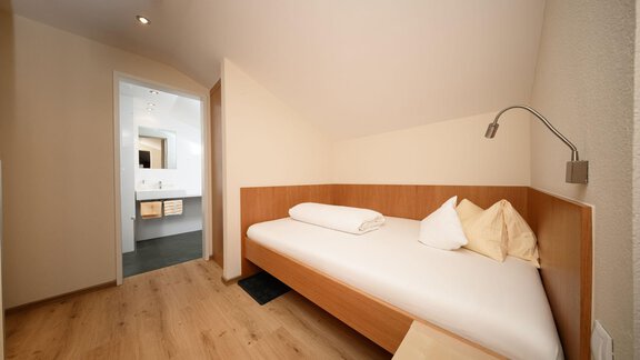 A simple bedroom with a single bed and a large window. The room has bright walls and a minimalist style. - Hotel Garni Maria Theresia - Sölden