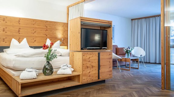 A modern hotel room with wooden decor and a comfortable double bed. Large windows provide plenty of daylight and a pleasant atmosphere. - Hotel Liebe Sonne - Sölden