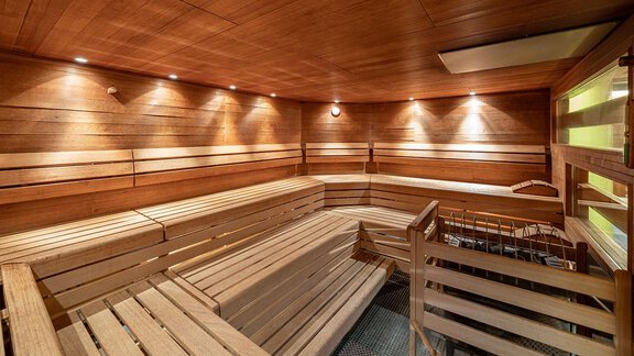 A modern sauna with warm wooden interior and soft lighting. The benches are made of wood and provide space for relaxation. - Hotel Liebe Sonne - Sölden