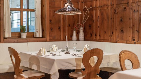 A cozy restaurant table with white tablecloths and elegant glasses. The wooden wall gives the room a warm atmosphere. - Hotel Liebe Sonne - Sölden