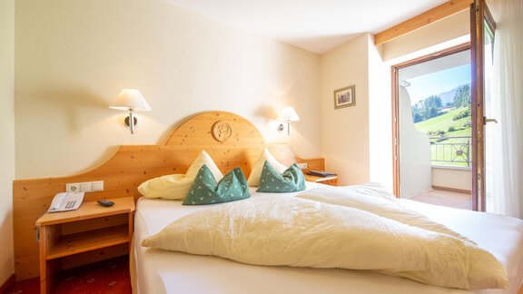A bright, inviting bedroom with two beds and green pillows. The view from the window offers a beautiful view of nature. - Hotelappart Peter - Sölden