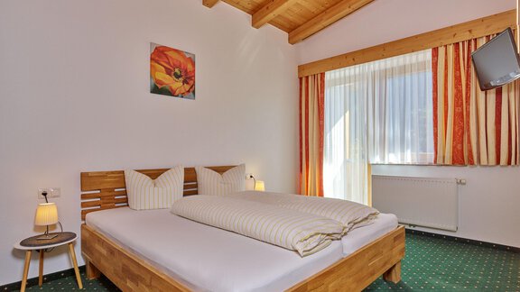 Ein gemütliches Schlafzimmer mit einem großen Doppelbett und hellem Holzdesign. Der Raum hat große Fenster, die viel Licht hereinlassen, und eine moderne Fernseher. - La Luna - Sölden