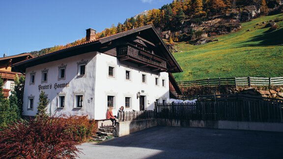 A traditional old building in a picturesque landscape. In the foreground, green meadows and colorful trees can be seen. - Landhaus Peater's Hoamat - Sölden