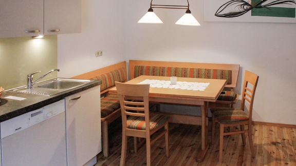 A cozy kitchen corner with a wooden table and padded benches. The space is well-lit and has a modern look. - Lutonia Appartements Sölden - Sölden
