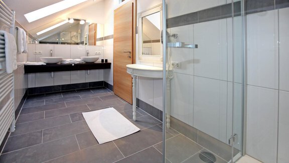 A modern bathroom with elegant fixtures and a large shower. The room is bright and spacious, with floor tiles in shades of gray. - Lutonia Appartements Sölden - Sölden