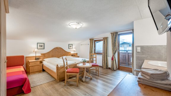 A cozy room with a large double bed and an additional single bed. The room has a balcony with a view outside and is modernly furnished. - Lyns Home - Sölden