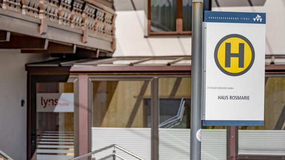 A bus stop with a sign for "Haus Rosmarie" can be seen. In the background, there is a building with a balcony railing. - Lyns Home - Sölden