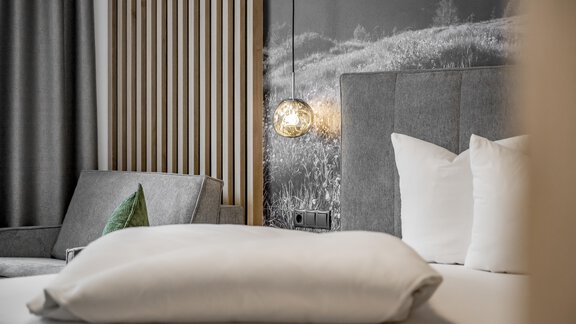 A modern bedroom with a comfortable bed and stylish pillows. In the background, a gray wall and a cozy sitting area are visible. - Marco's Mountain Home - Sölden