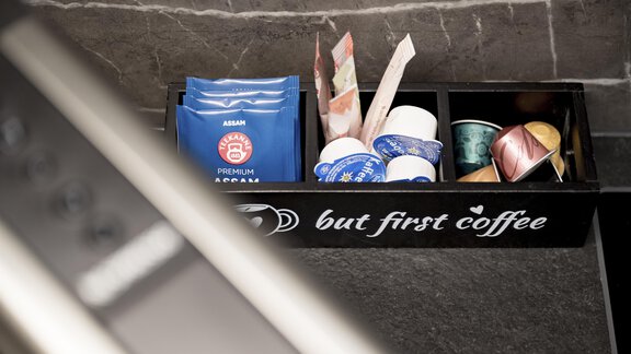 A coffee station with various types of coffee and accessories. On a black container, the phrase "but first coffee" is written. - Marco's Mountain Home - Sölden