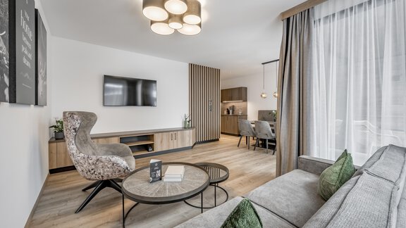 A modern living room with a cozy sofa and an elegant armchair. The room has large windows and a stylish ceiling lamp. - Marco's Mountain Home - Sölden