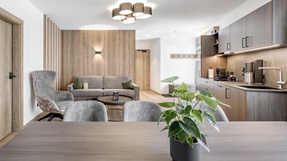A modern living room with a cozy sofa and a dining area. The decor is stylish and bright, with wood and green tones. - Marco's Mountain Home - Sölden