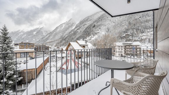 A balcony with a table and chairs, surrounded by snow-covered mountains. The landscape is calm and wintry. - Marco's Mountain Home - Sölden