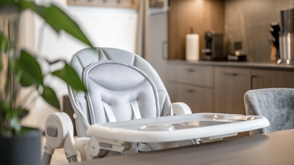 A stylish high chair in a modern kitchen. The high chair features a bright design and is placed at a wooden table. - Marco's Mountain Home - Sölden