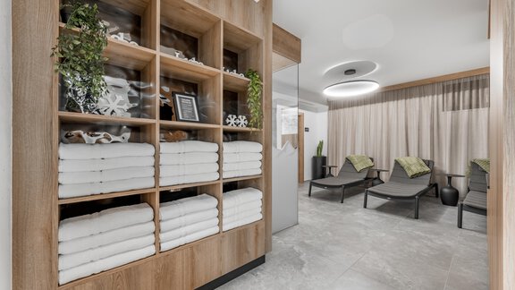 A modern relaxation room with stacked towels and stylish loungers. The warm wood appearance and soft lighting create an inviting atmosphere. - Marco's Mountain Home - Sölden