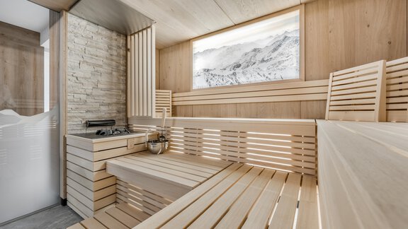 A modern sauna interior made of light wood with comfortable loungers. A mountain landscape is visible through a large window. - Marco's Mountain Home - Sölden