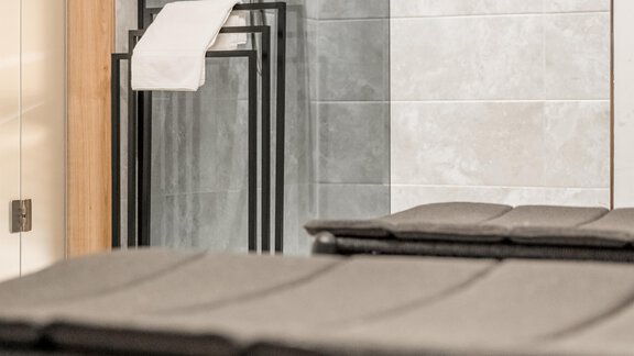 A modern wellness area with comfortable loungers and an elegant shower. The walls are lined with gray tiles, creating a relaxing atmosphere. - Marco's Mountain Home - Sölden