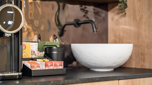 A modern kitchen unit with an elegant sink and a coffee machine. On the countertop, there are various tea bags and accessories. - Marco's Mountain Home - Sölden