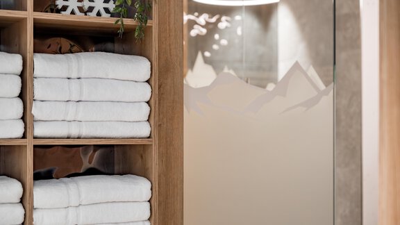 An elegant wellness area with neatly stacked towels and a glass door showcasing a mountain landscape. The ambiance feels modern and inviting. - Marco's Mountain Home - Sölden