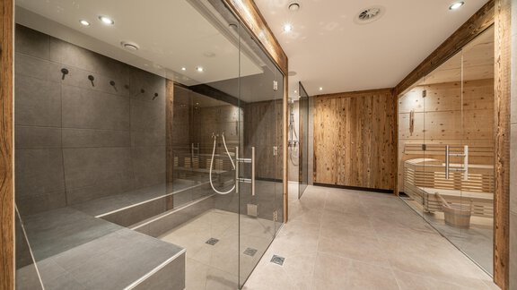 A modern spa with glass shower cubicles and wood paneling. The room exudes calm and elegance. - Pension Miramonte - Sölden