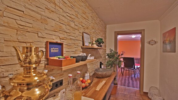 An inviting hallway with a stone feature and decorative elements. In the background, a living area with a seating area is visible. - Pension "Zur alten Mühle" - Sölden
