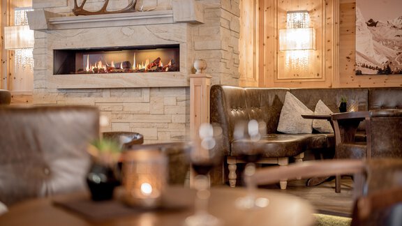 A cozy interior view of a restaurant with a fireplace and brown leather benches. An inviting atmosphere with wood and stone accents. - Regina Hotelsuites - Sölden