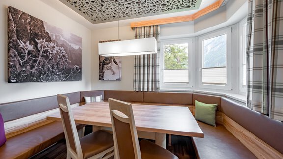 A modern dining room with a cozy seating area and a large table. The walls are decorated with beautiful pictures and the windows provide plenty of natural light. - Residenz Allegra - Sölden