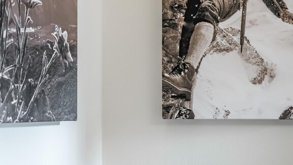 A cozy restaurant area with a bench and a checkered cushion. On the wall hangs a black and white picture of a mountaineer in a snowy landscape. - Residenz Allegra - Sölden