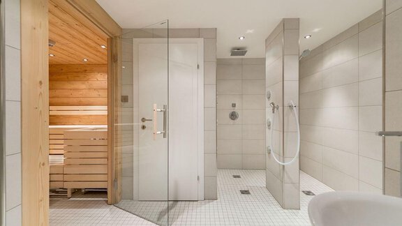 A modern bathroom with a sauna and two shower areas. The walls are light-tiled and the lighting is soft. - Revmatologická poradna Appt Top 4 - Sölden