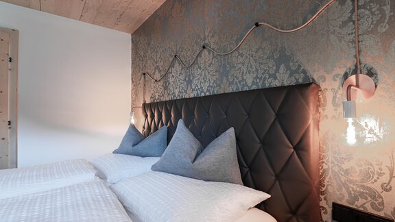 A modern bedroom with a stylish, upholstered headboard and tasteful wall decor. Soft lighting creates a cozy atmosphere. - Selda Chalet - Sölden