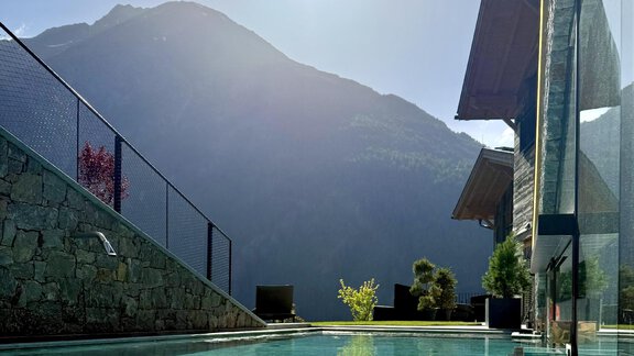 A quiet pool with clear water, surrounded by a mountain panorama. The sun is shining and the view is picturesque. - The Peak Sölden - Sölden