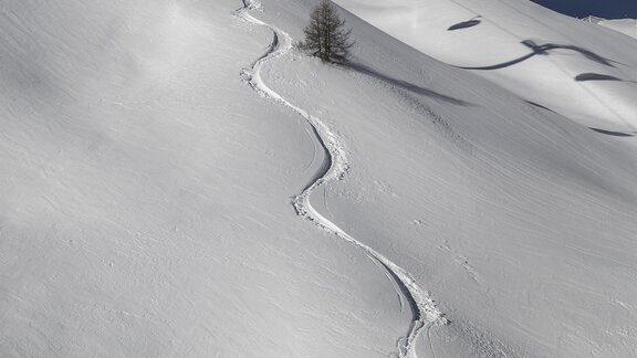 A cable car travels over a snowy slope. In the background, clear, blue skies and ski tracks are visible. - Top Apart Daniela - Sölden
