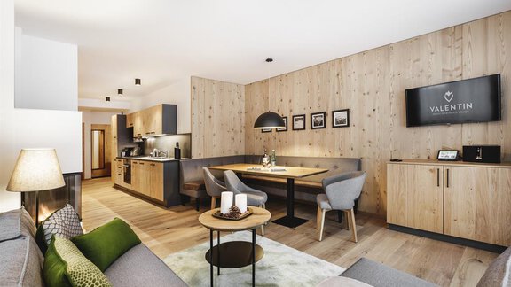 A modern living room with wooden paneling and elegant furniture. The open kitchen and dining area create an inviting atmosphere. - Valentin Design Apartment - Sölden