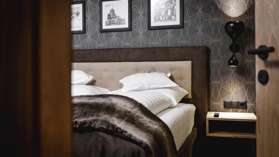 A modern bedroom with a comfortable bed and decorative pictures on the wall. The soft lighting and stylish furnishings create an inviting atmosphere. - Valentin Design Apartment - Sölden