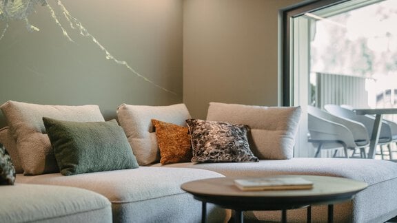 A modern living room with a comfortable, bright sofa and colorful cushions. The room has large windows that let in plenty of daylight. - VIBES Sölden - your alpine homebase - Sölden