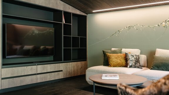 A modern living space with a cozy sofa and a television on the wall. The wall is in soft colors and the decoration is minimalist and elegant, painted by Anne-Sophie. - VIBES Sölden - your alpine homebase - Sölden
